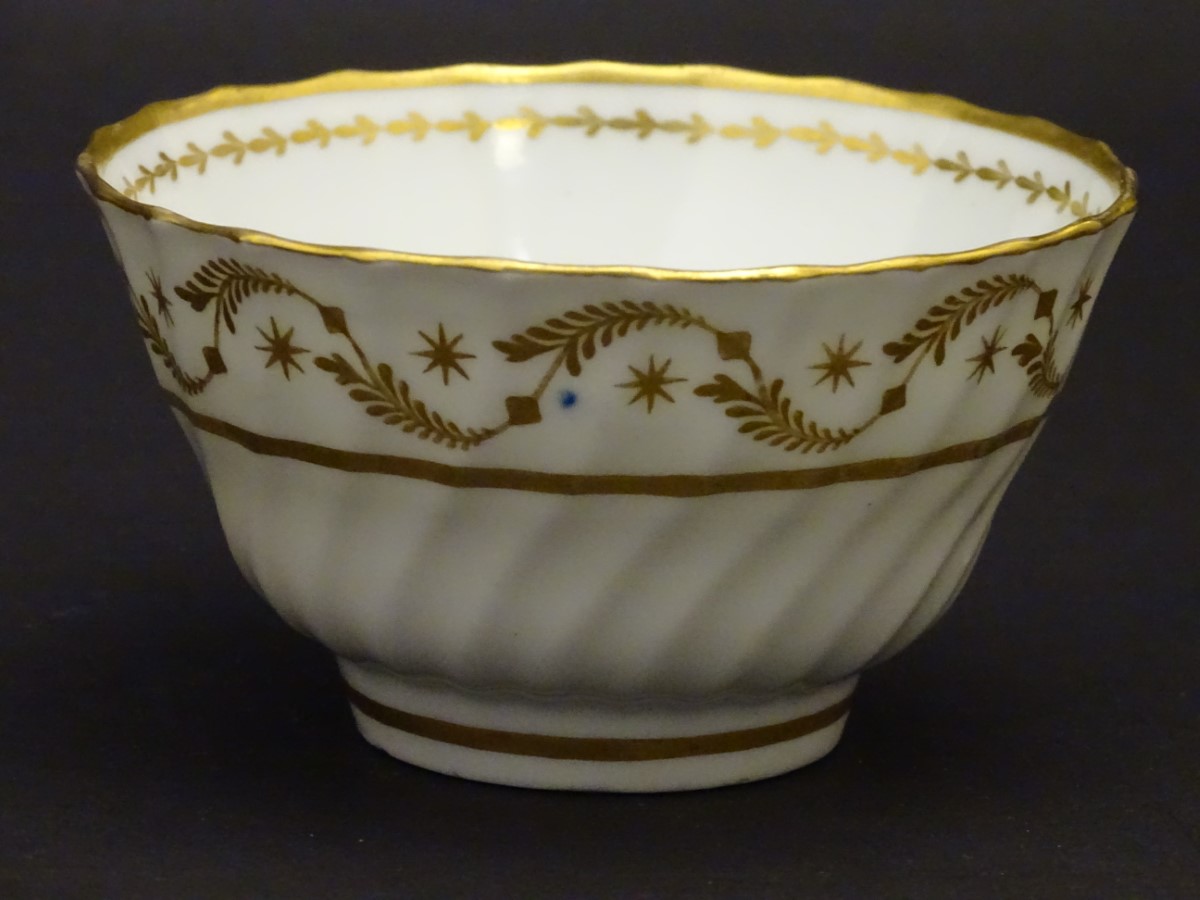 A 19thC white porcelain tea bowl with ribbed sides and gilt decoration of stylised foliage and