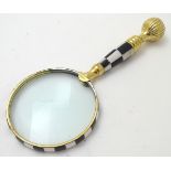 A 21stC magnifying glass with a checkered black and white frame and handle,