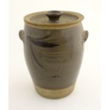 A two tone studio pottery lidded stoneware pot with twin handles and stylised brushwork decoration.