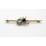 A yellow metal bar brooch set with spider to centre with turquoise / aqua coloured stone and blue