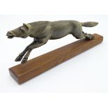 A 20thC carved horn model of a horse on a wooden base. 9" long.