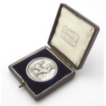 A hallmarked silver medallion depicting cockerels,
