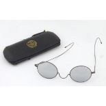 A cased pair of Edwardian spectacles / glasses with a steel frame,
