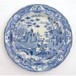 A Spode blue and white plate decorated with a stylised landscape, with trees, flowers, bridges,