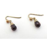 Yellow metal drop earrings set with facet cut garnet drops.