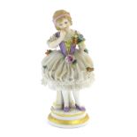 A German porcelain figure of a flower girl with a porcelain lace skirt on a circular base with gilt