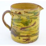 A 19thC studio pottery slipware jug with a yellow ground. Indistinct incised mark under. Approx.