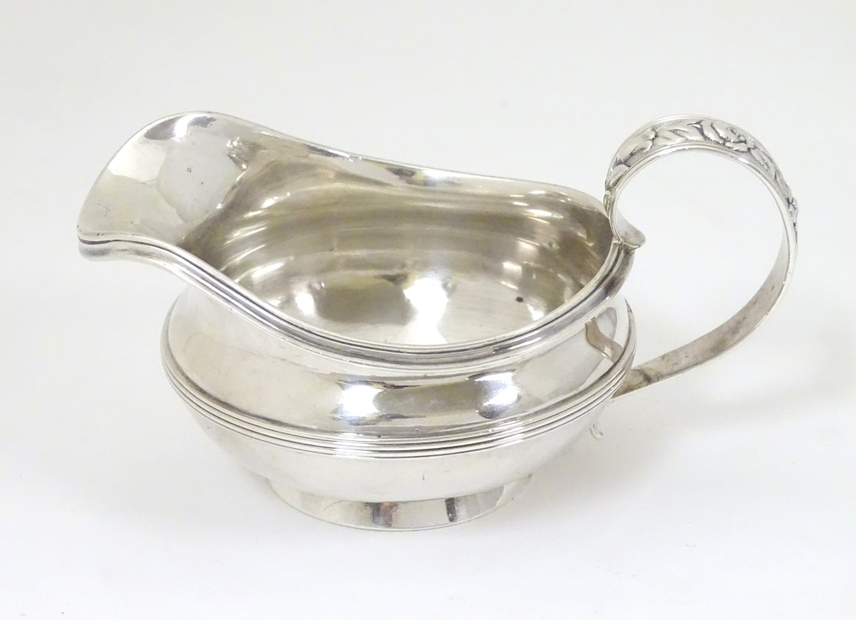 A silver jug / sauce boat with floral decoration to handle hallmarked London 1826 maker William