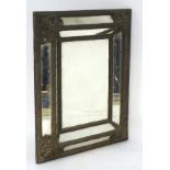 A 19thC cushion mirror with embossed metal lining and heavily decorated corners,