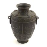 An Oriental bronze vase with twin ring handles formed as stylised masks.