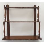 An early 20thC set of mahogany wall shelves with turned supports and three shaped tiers.