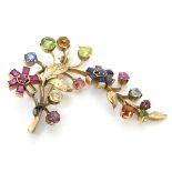 A gold brooch of floral foliate form set with a profusion of semi precious stones including pink,