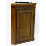 An 18thC oak corner cupboard with a crossbanded door having decorative stringing to the centre,