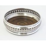 A silver bottle coaster with fret work decoration and turned wooden base.