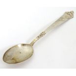 A Continental .830 silver teaspoon with scroll decoration to handle.