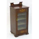 An early 20thC mahogany music cabinet with a shaped up stand decorated with marquetry detailing