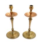 WAS Benson : A pair of Arts and Crafts brass and copper candlesticks in the manner of W.A.S.