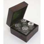 A set of four 19thC glass scent bottles and stoppers with cut decoration within a wooden box.