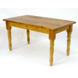 An early 20thC pine kitchen table with a rectangular top above turned tapering legs.