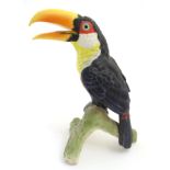 A W. Goebel model of a green billed toucan bird perched on a branch.