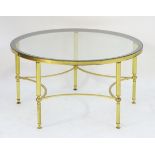 A mid 20thC glass top table with a brass base and star formed stretcher.