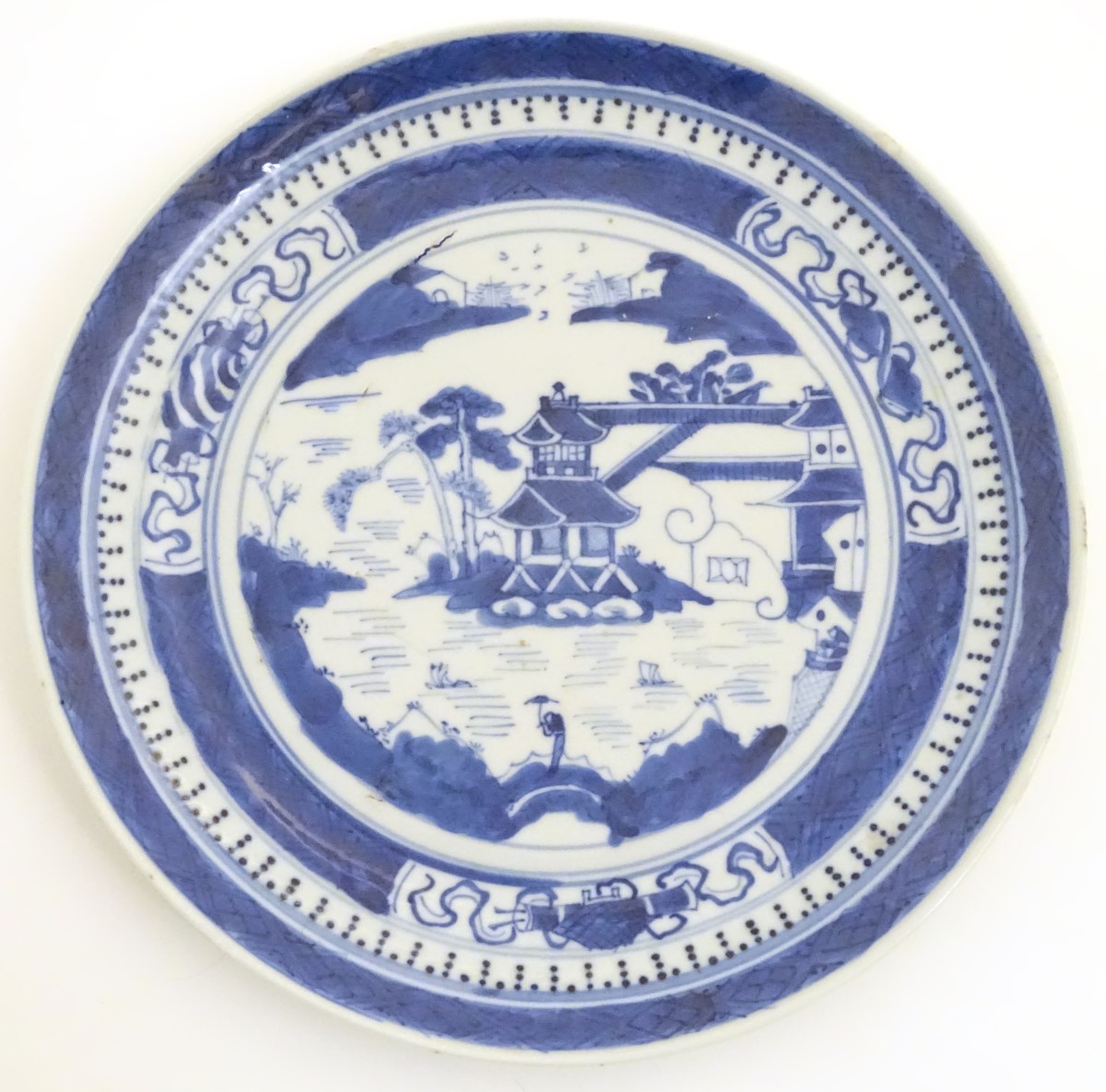 A Chinese blue and white plate with hand painted decoration depicting a pagoda on an island,