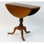 A late 19thC drop flap table standing on a pedestal base with three cabriole legs.