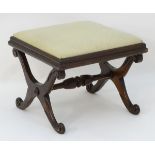 A 19thC mahogany stool with a drop in seat above a stepped surround and x frame supports united by
