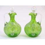 A pair of Victorian green glass small decanters / carafes with white enamel and gilt decoration and