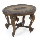 An early 20thC Anglo Indian table with an oval carved table top above four elephant formed supports