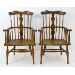 A pair of 19thC comb back Windsor chairs with swept arms and naive carving,
