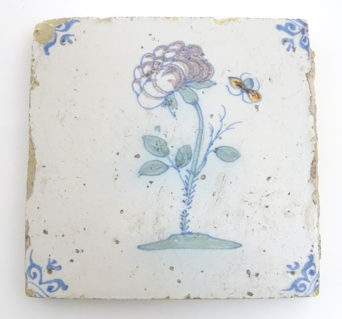 A 17thC Delft tile depicting a flower and a flying insect, with blue ox-head corner motifs. Approx. - Image 3 of 4