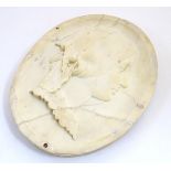 A marble / composite oval wall plaque with a relief depiction of a Victorian woman in profile.