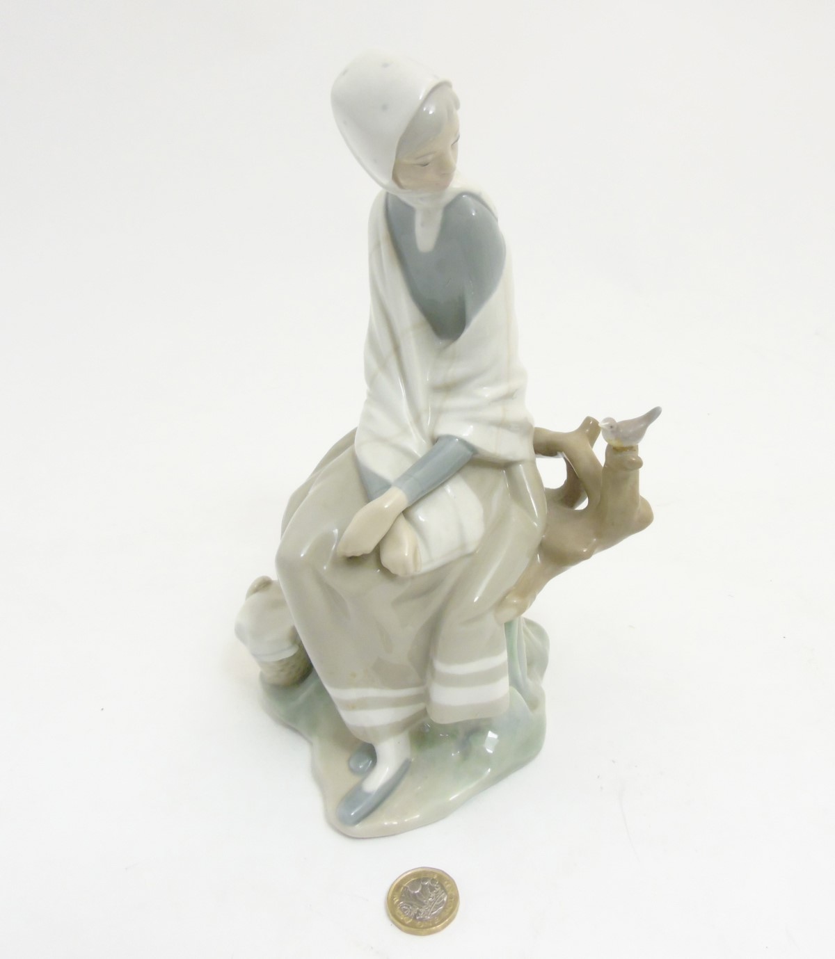 A Lladro 'New Shepherdess' figurine of a girl sat watching a bird, makers mark to base,