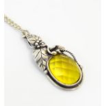 A silver pendant set with oval facet cut citrine with a foliate mount, the chain 20” long.