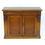 A late 19thC mahogany chiffonier with an inset leather top above two panelled cupboard doors