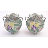 A pair of Continental twin handled vases of squat form with lobed rims and hand painted floral and