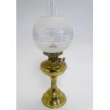 A 20thC oil lamp with brass base with column stand and integral reservoir supporting a frosted and