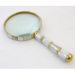 A 20thC magnifying glass with a brass and mother of pearl frame and handle. Approx. 8 1/2" long.