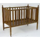 An early 20thC baby crib of slatted construction with a fall front,