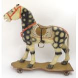 Toy: A 19thC Continental folk art papier mache pull along horse on a wooden base with a wheel four