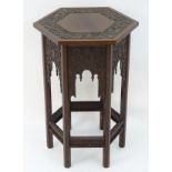 A walnut Liberty style table with a hexagonal carved top above six matching carved facades with