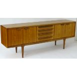 A Retro Danish teak sideboard with cupboards to both sides and drawers to the centre and standing