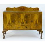 A mid 20thC walnut sideboard with a shaped up stand above three short drawers flanked by two