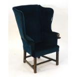 A 19thC wingback armchair with scrolled arms and standing on squared legs with a H - stretcher.
