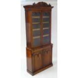 A late 19thC mahogany bookcase with a carved pediment above a moulded cornice and two glazed doors