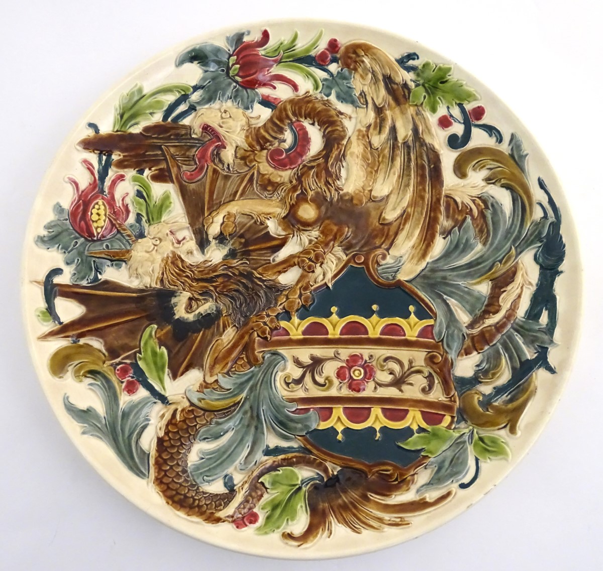 A large 19thC Austrian charger decorated in relief with two fighting griffins / dragons with a