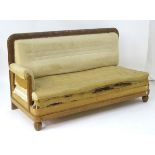 An early / mid 20thC daybed / sofa with a carved show wood frame and raised on gadrooned bun feet.