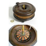 A 19thC treen turned fruitwood small proportion roulette wheel raised on three feet.