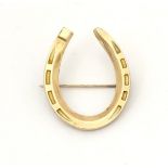 A gold brooch formed as a horseshoe.